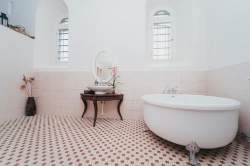 uma casa de banho com uma banheira branca e um espelho. em Mooste Viinavabriku Hotell & Restoran em Mooste