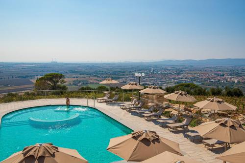 a swimming pool with chairs and umbrellas at Castello Bonaria Wine & Spa Resort in Campiglia Marittima