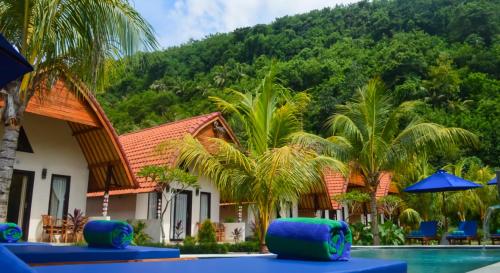 a resort with a swimming pool and palm trees at Penida Bay Village in Nusa Penida