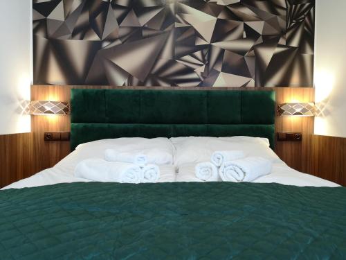 a bedroom with a green bed with towels on it at Hotel Biele Studničky Dargov in Dargov