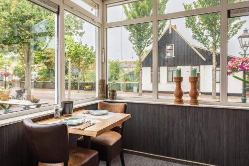 a table and chairs in a room with windows at Hotelletje de Veerman in Oost-Vlieland