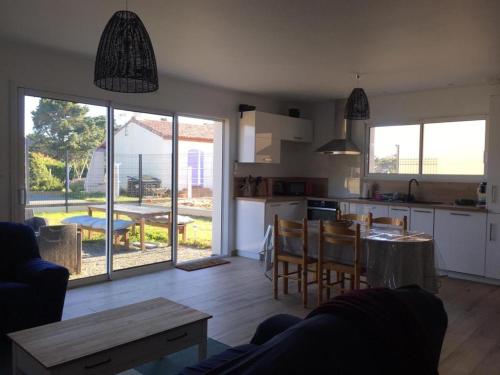 uma cozinha e uma sala de estar com mesa e cadeiras em Maison cosy à 400 m de la mer! em Saint-Vincent-sur-Jard