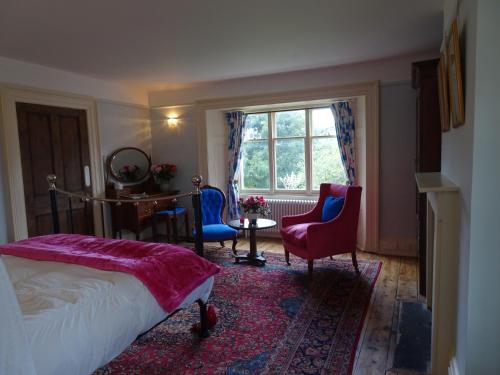 a bedroom with a bed and chairs and a window at Redlynch Lodge in Redlynch