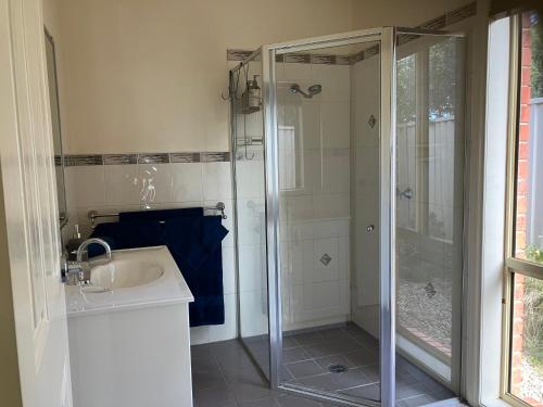 a bathroom with a sink and a glass shower at James Court Suite in Rutherglen