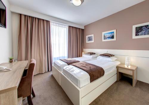 a hotel room with a bed and a table and a desk at Hotel Argentum in Mostar