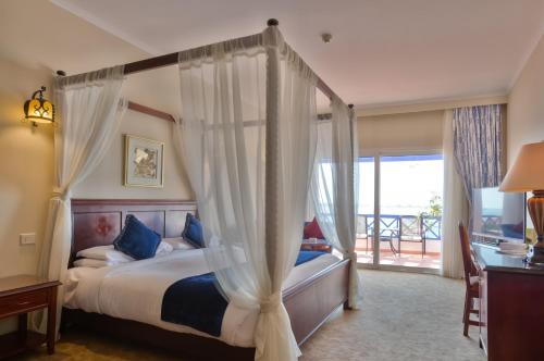 a bedroom with a canopy bed and a balcony at Porto Marina Resort & Spa Al Alamein in El Alamein