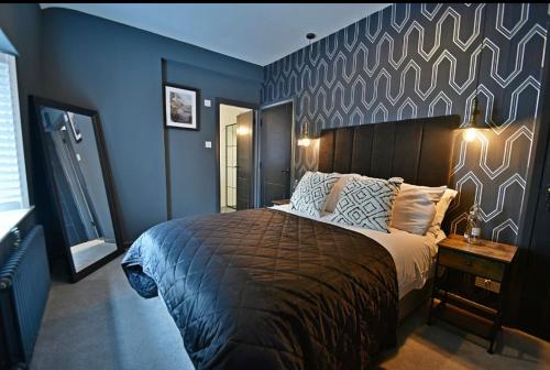 a bedroom with a large bed with blue walls at Boutique cottage set in historic town of Clitheroe in Clitheroe