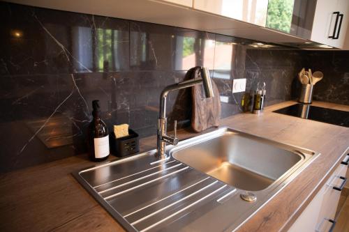 a stainless steel sink in a kitchen with a bottle of wine at L'ÉLÉGANCE DU VIGNY in Divonne-les-Bains