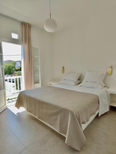a white bedroom with a large bed and a window at ARK Tinos in Agios Ioannis Tinos
