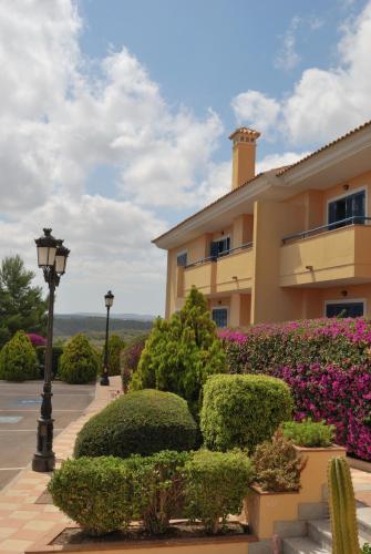 a building with bushes and a street light and flowers at Hotel Golf Campoamor in Dehesa de Campoamor