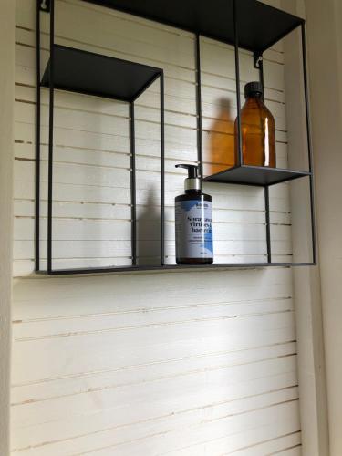 Un estante en una pared con dos botellas. en Glampingtält en Torsby