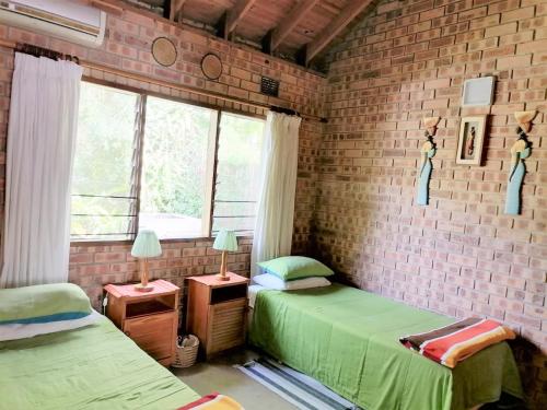 a room with two beds and a brick wall at St Lucia Wilds in St Lucia