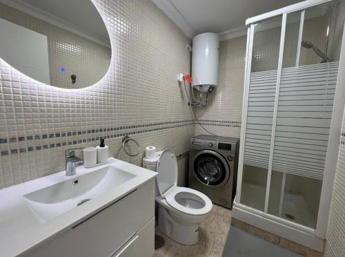 a bathroom with a sink toilet and a washing machine at Las Palmeras in Benalmádena