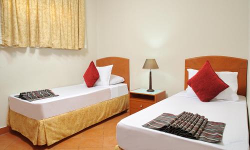 Cette chambre comprend 2 lits avec des oreillers rouges. dans l'établissement Golf Porto Marina Hotel Apartments Al Alamein, à El Alamein