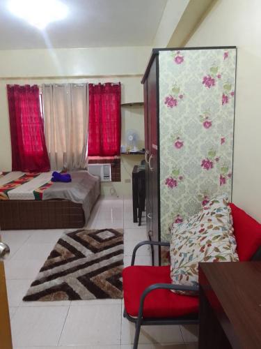 a living room with two beds and a red chair at Aliyahs’s Place: Staycation in Valley Golf Cainta in Cainta