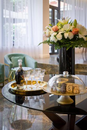 a glass table with a vase of flowers and drinks on it at Hotel Corner in Split