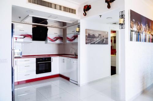 a kitchen with white cabinets and red accents at Almog Haifa Israel Apartments מגדלי חוף הכרמל in Haifa