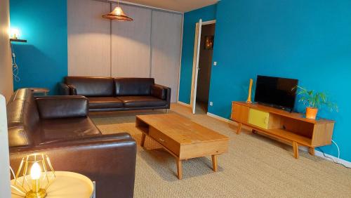 a living room with a leather couch and a tv at Gite du Hameau in Voiteur