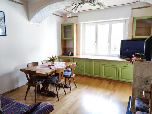une cuisine avec des placards verts et une table en bois dans l'établissement Appartamento Vanoi nel cuore verde del Trentino, à Canal San Bovo
