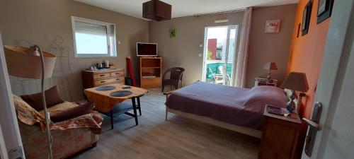 a bedroom with a bed and a table and a chair at Chambre d'hôte Fleur de Potager in Les Sables-dʼOlonne