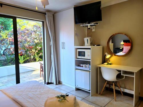a room with a desk and a microwave and a window at Suite 9- Deja' Blu Bed and Breakfast- East London in East London
