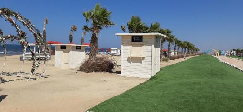 a row of small shelters on a beach with palm trees at Porto Said Hotel & Spa in Port Said