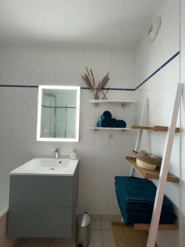 ein Badezimmer mit Waschbecken und Spiegel in der Unterkunft Appartement plage restaurant et parking privatif in Wimereux