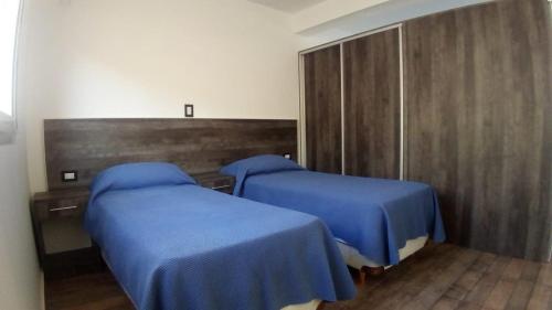 2 camas en una habitación de hospital con sábanas azules en Abril Dptos Temporarios en San Juan