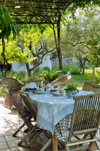 een tafel met een wit tafelkleed en stoelen en bomen bij la maison des Olivettes in Uzès