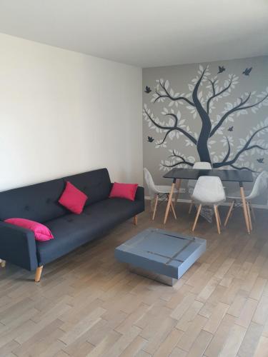a living room with a blue couch and a tree mural at Le Baron in Le Blanc-Mesnil