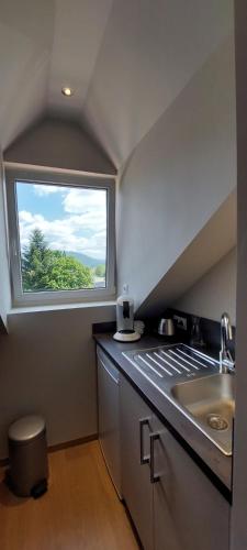 une cuisine avec un évier et une fenêtre dans l'établissement La Chouette, à Gérardmer