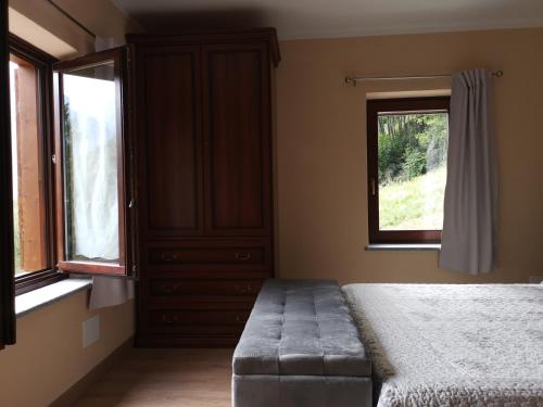 a bedroom with a bed and a dresser and two windows at Al Drit in Verrès