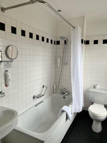 a bathroom with a tub and a toilet and a sink at Manor Hotel by Greene King Inns in Yeovil