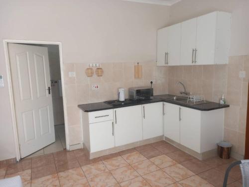 a kitchen with white cabinets and a sink and a door at Fabulous Rest Inn in Francistown
