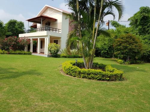 a white house with a palm tree in a yard at Celestial Resorts, Retreat in Nature in Phanda