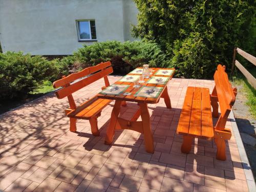 a wooden picnic table and two benches on a brick patio at Apartmány NIVA in Široká Niva