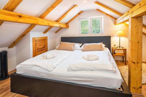 a large white bed in a room with wooden ceilings at Stone Garden Villa, Heated Pool & Outdoor Cinema in Trilj
