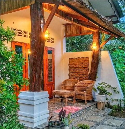 a porch of a house with two wicker chairs at Sumatra Orangutan Discovery Villa in Bukit Lawang