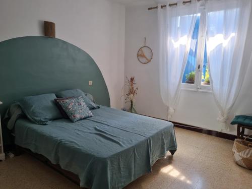 a bedroom with a bed with a blue blanket and a window at Maison Gemenos in Gémenos