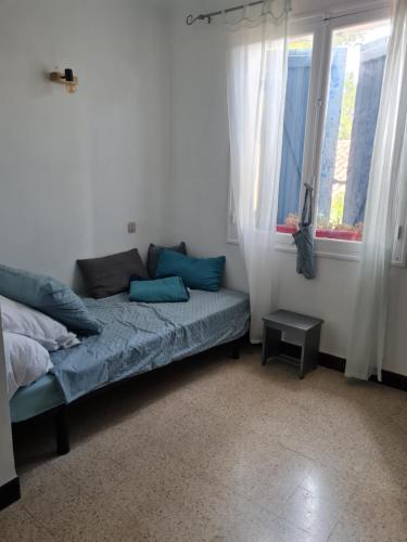 une chambre avec un lit avec des oreillers bleus et des fenêtres dans l'établissement Maison Gemenos, à Gémenos