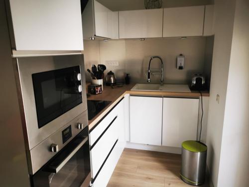 a small kitchen with white cabinets and a sink at APPARTEMENT COSY LIBOURNE in Libourne
