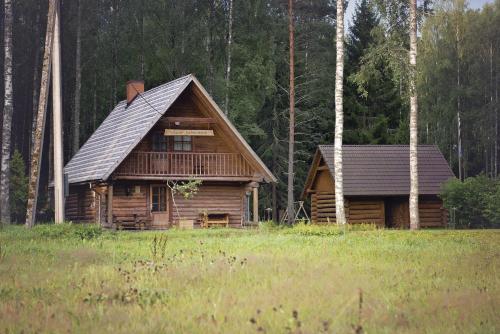 a log cabin in a field next to a forest at Aasa Holiday Homes in Kärsu