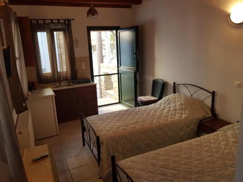 a bedroom with two beds and a kitchen with a window at GUEST HOUSE KALLIOPI in Kómi