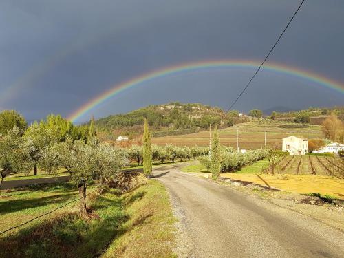 a rainbow over a road in a field with trees at Clos Saint-Michel Resort & Spa in Malaucène