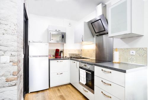 a white kitchen with white cabinets and appliances at APPART PREMIUM DU LYS Balcon amenage Parking gratuit in Dammarie-lès-Lys