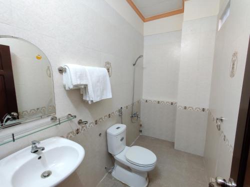 a white bathroom with a toilet and a sink at Winter Spring Homestay Center in Can Tho