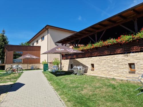 a building with a patio with tables and umbrellas at Topolský pivovar, restaurace a penzion in Topolná