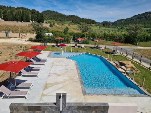 a swimming pool with umbrellas and lounge chairs at Hébergement Insolite avec SPA - Foudrenlair in Bize-Minervois