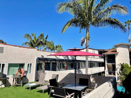 Eine Frau, die mit einem Regenschirm am Tisch sitzt. in der Unterkunft Beachside Inn in Santa Barbara