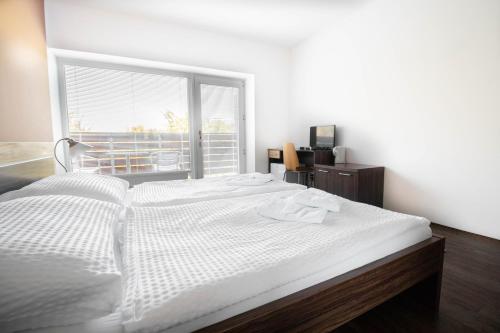 a large white bed in a room with a window at Topolský pivovar, restaurace a penzion in Topolná